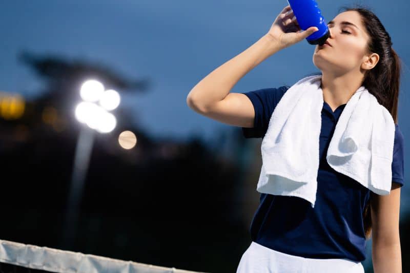 Tennis woman s'hydratant après match